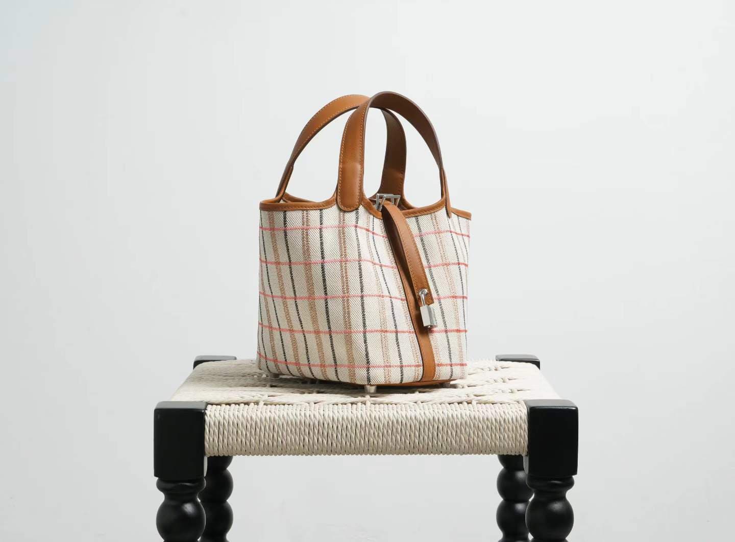 LINJIN LUXURY Picotin Lock 18 style bag in gold leather and plaid canvas, displayed on a natural woven stool against a clean white background - 2