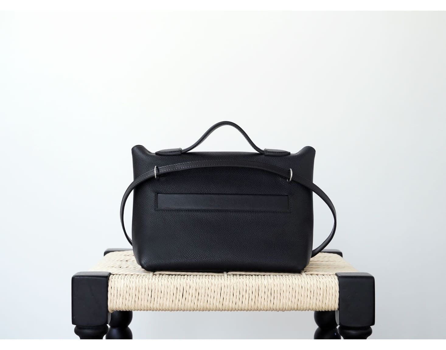 Front view of an Etoupe grey pebbled leather mini doctor bag with white contrast stitching and silver hardware, placed on a white woven stool - 3