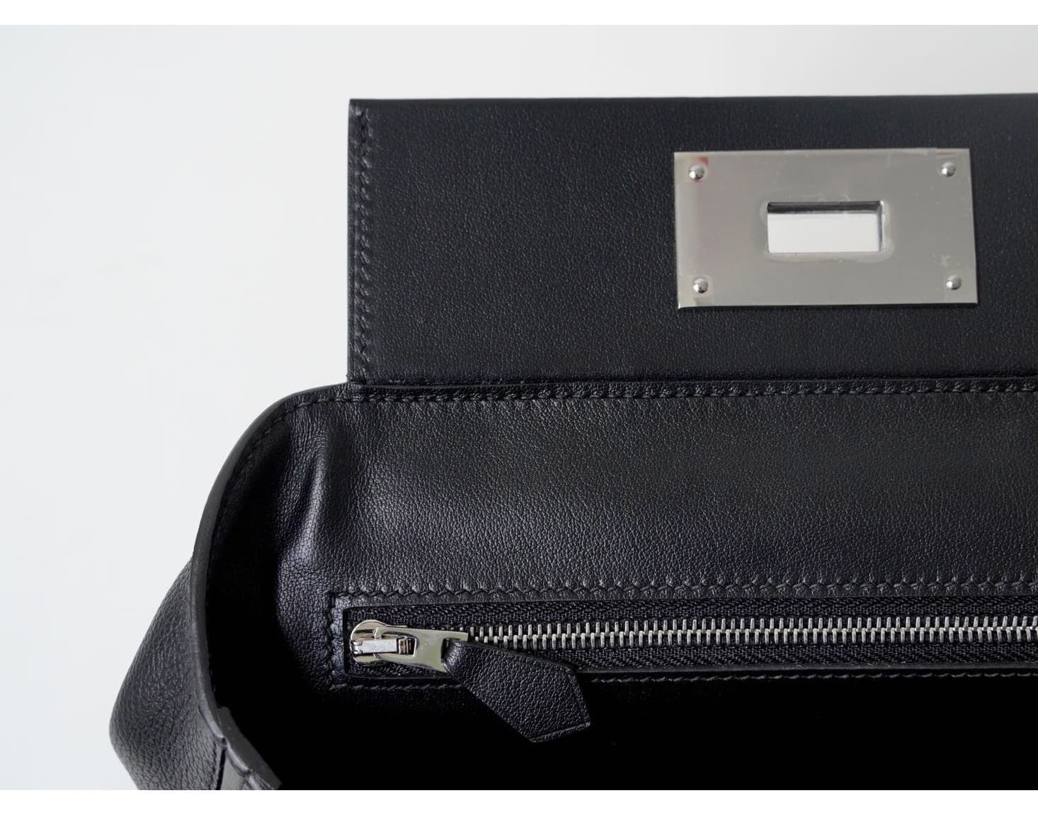 Front view of an Etoupe grey pebbled leather mini doctor bag with white contrast stitching and silver hardware, placed on a white woven stool - 5