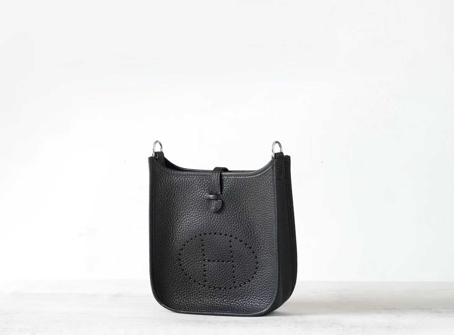 Linjin Luxury togo cowhide crossbody bag with perforated H-motif front panel, snap tab closure, and adjustable canvas strap with silver-tone hardware, on a woven rattan bench - 2