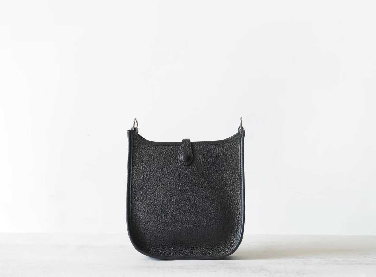 Linjin Luxury togo cowhide crossbody bag with perforated H-motif front panel, snap tab closure, and adjustable canvas strap with silver-tone hardware, on a woven rattan bench - 3
