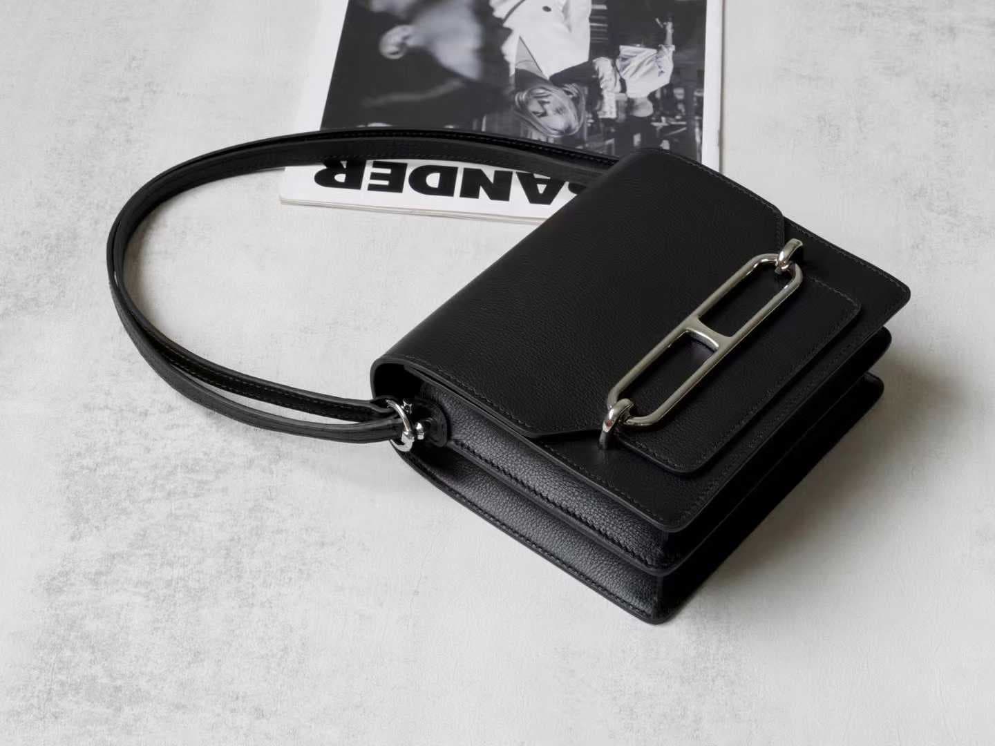 Front view of LINJIN LUXURY Roulis 18 shoulder bag in black Evercolor leather, showcasing the silver anchor-link buckle on a woven stool - 2