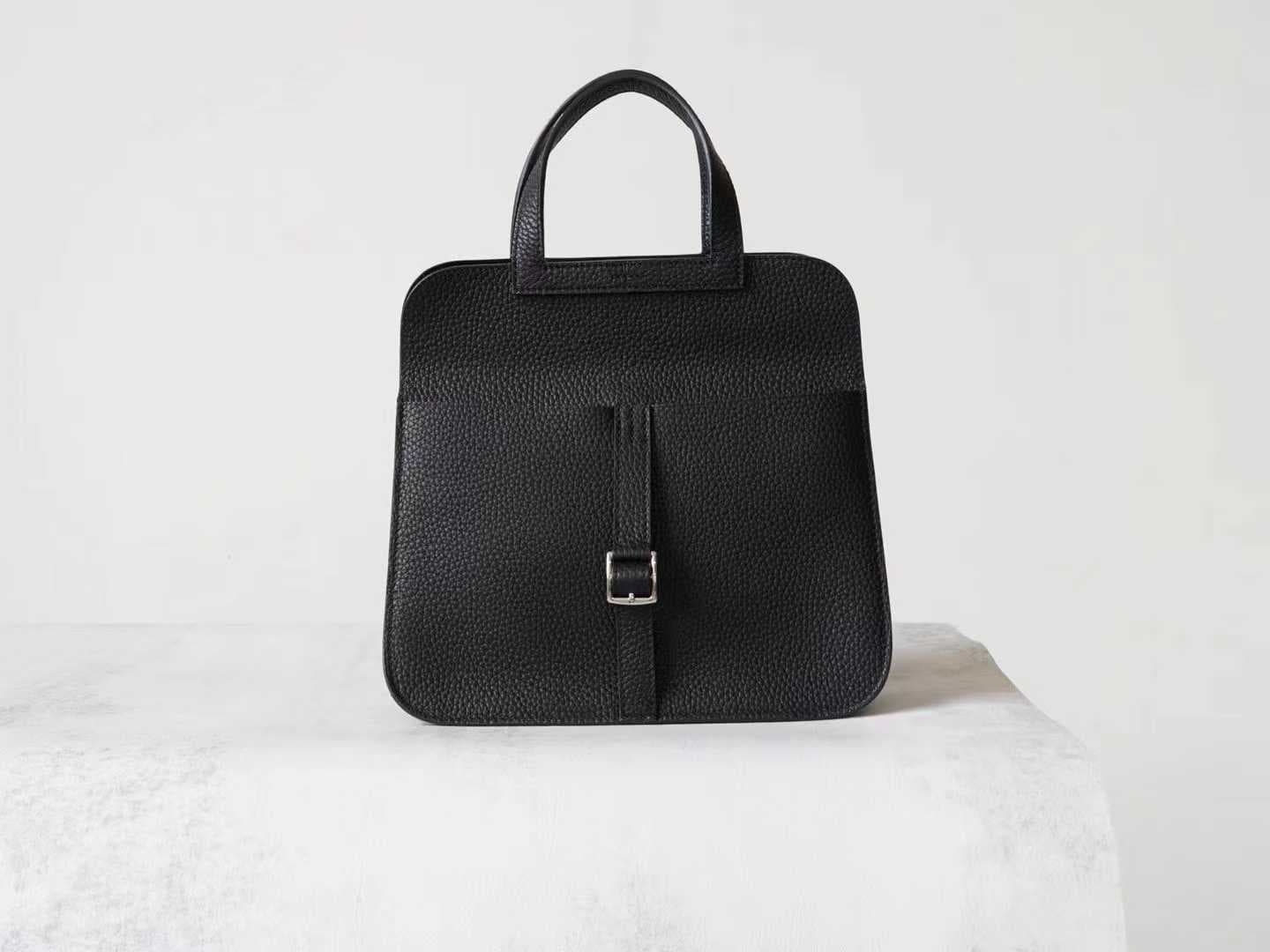 Minimalist black pebbled leather crossbody bag with a front buckle detail and long shoulder strap on a white background | LinJin - 2