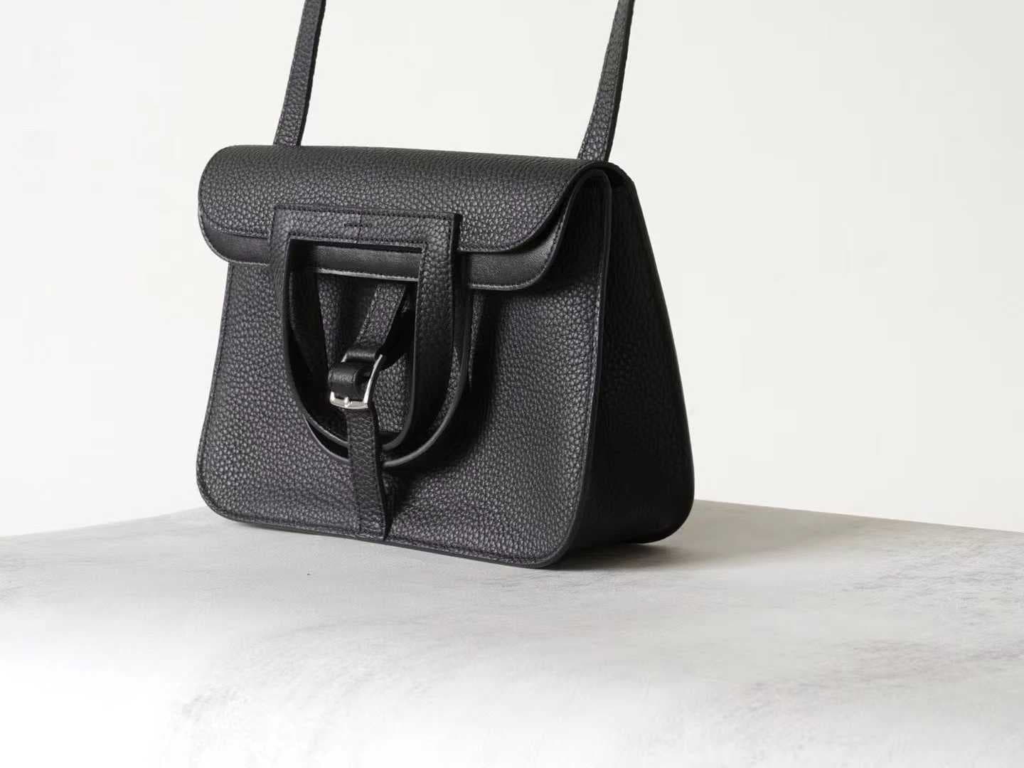 Minimalist black pebbled leather crossbody bag with a front buckle detail and long shoulder strap on a white background | LinJin - 3