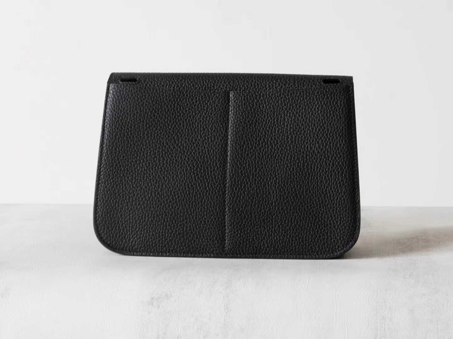 Minimalist black pebbled leather crossbody bag with a front buckle detail and long shoulder strap on a white background | LinJin - 4