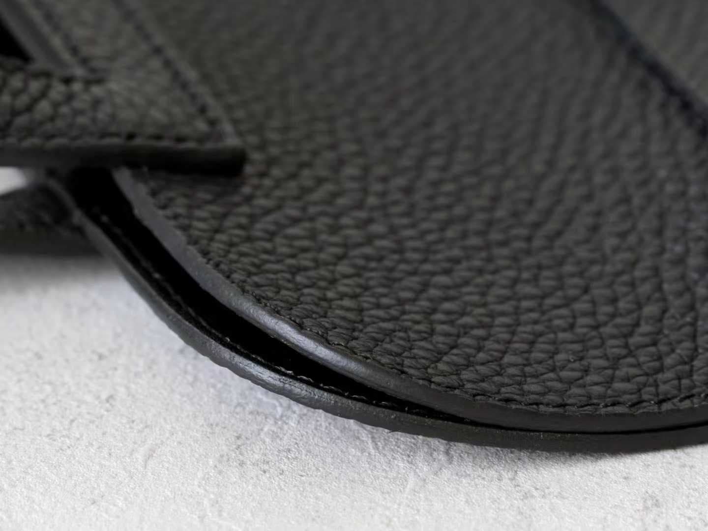 Minimalist black pebbled leather crossbody bag with a front buckle detail and long shoulder strap on a white background | LinJin - 8