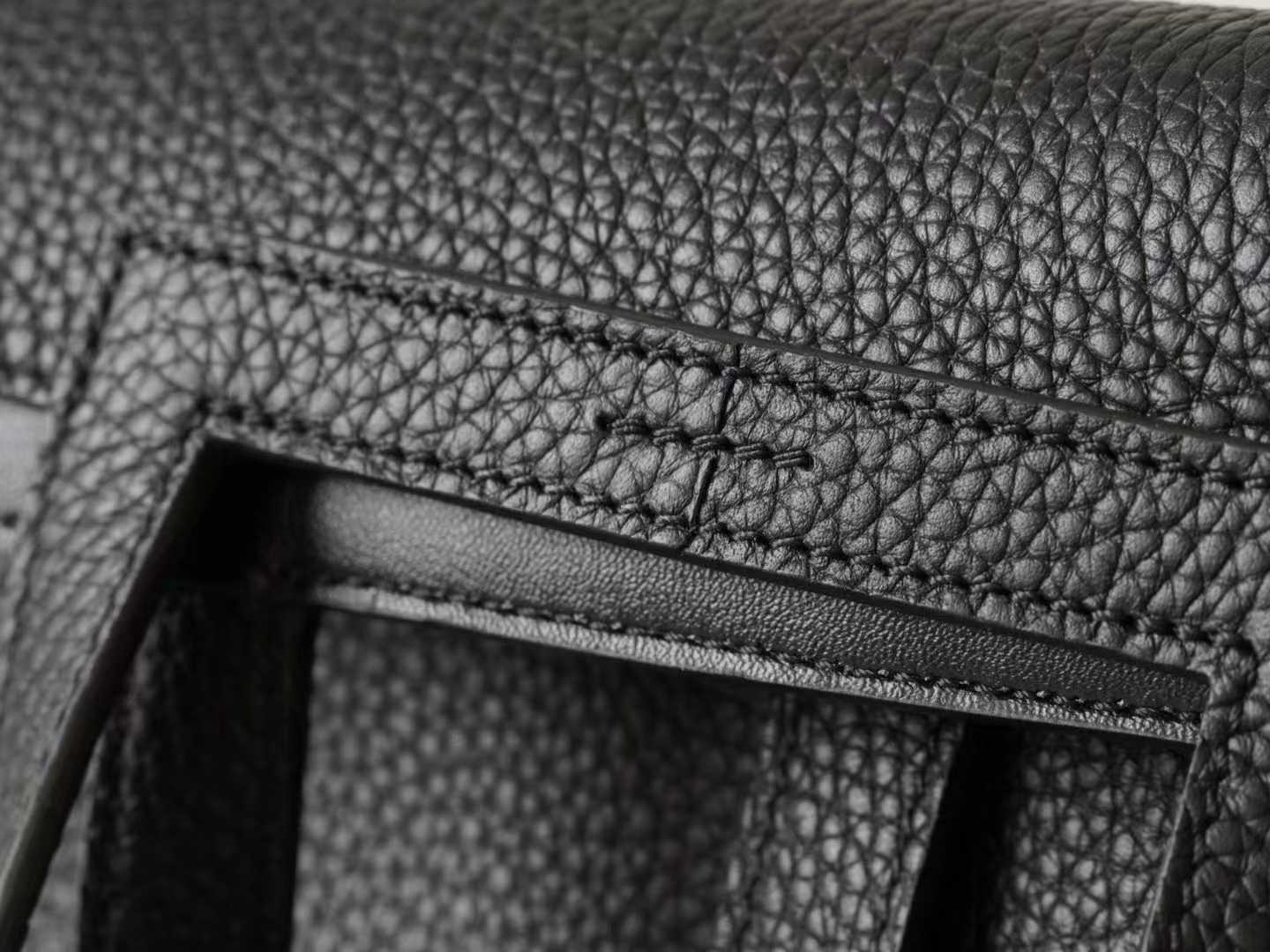 Minimalist black pebbled leather crossbody bag with a front buckle detail and long shoulder strap on a white background | LinJin - 9
