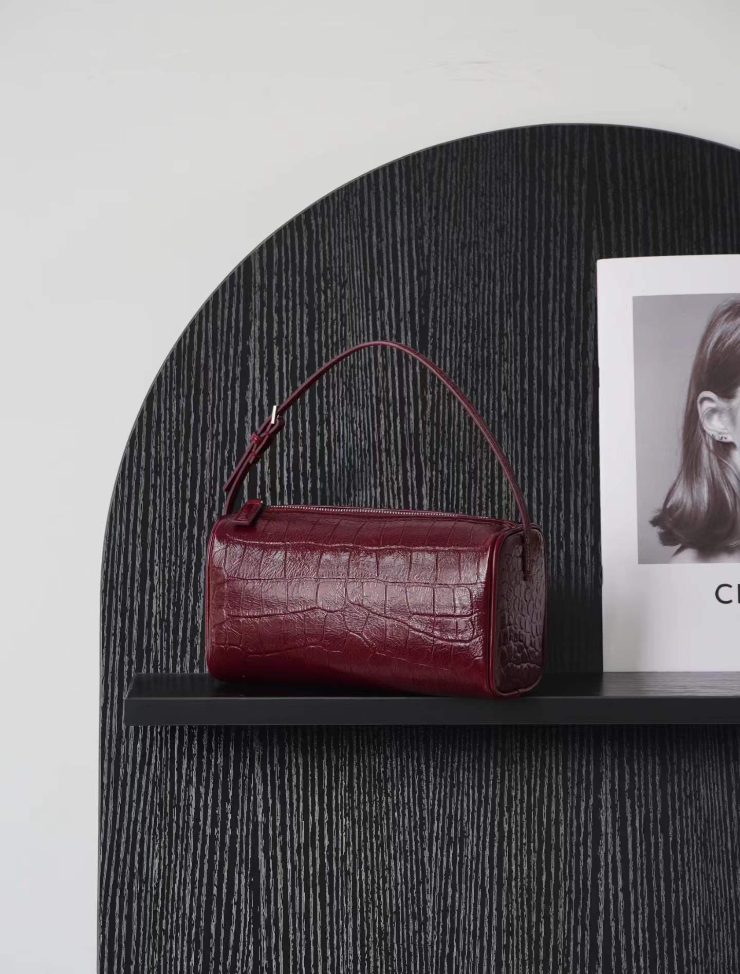 Linjin Luxury croc-embossed lambskin cylinder bags in black, cream, and burgundy, stacked on a woven rattan bench with black bobbin legs, silver zip hardware and adjustable shoulder straps - 2