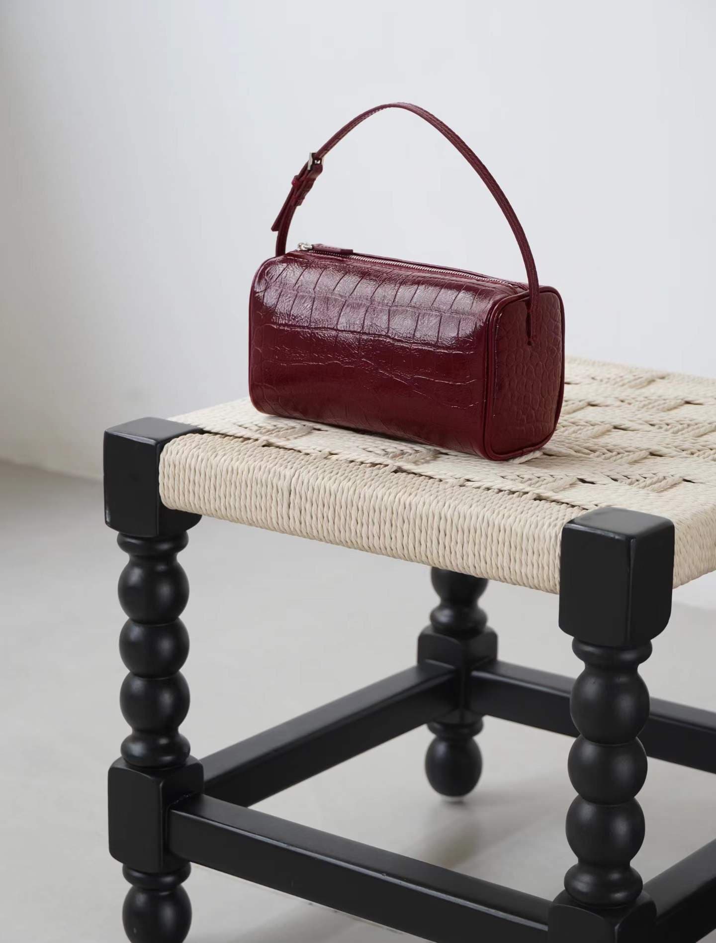 Linjin Luxury croc-embossed lambskin cylinder bags in black, cream, and burgundy, stacked on a woven rattan bench with black bobbin legs, silver zip hardware and adjustable shoulder straps - 3
