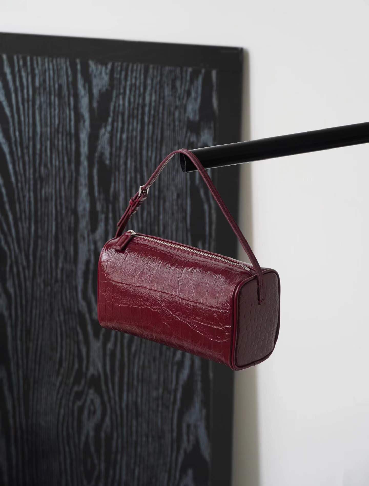 Linjin Luxury croc-embossed lambskin cylinder bags in black, cream, and burgundy, stacked on a woven rattan bench with black bobbin legs, silver zip hardware and adjustable shoulder straps - 4